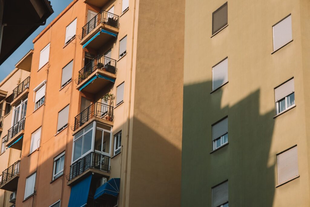 Low angle view of sunlit apartment buildings with balconies in Valencia, Spain.